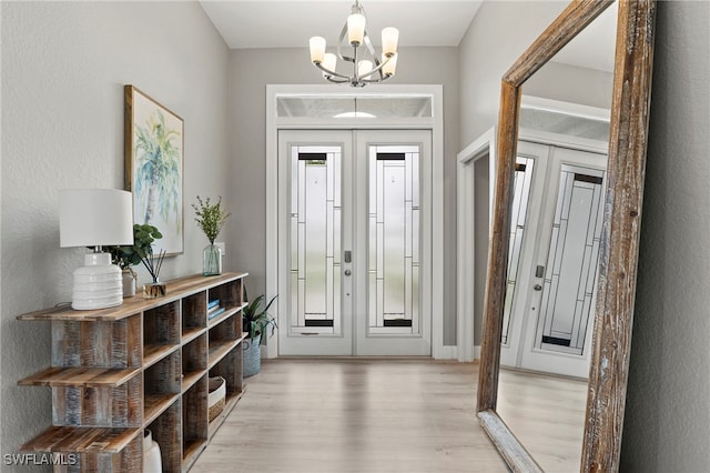 entrance foyer with french doors, an inviting chandelier, and light hardwood / wood-style flooring