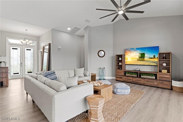 living room with ceiling fan with notable chandelier, light wood-type flooring, and lofted ceiling