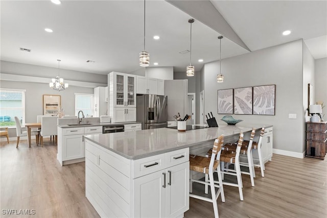 kitchen featuring stainless steel refrigerator with ice dispenser, a spacious island, sink, white cabinetry, and dishwashing machine