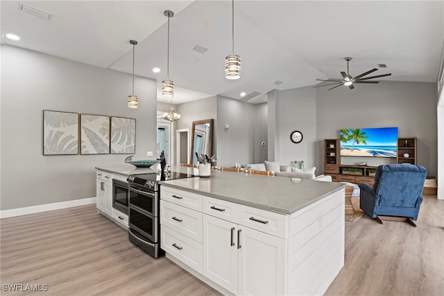 kitchen with light hardwood / wood-style floors, pendant lighting, lofted ceiling, white cabinets, and appliances with stainless steel finishes