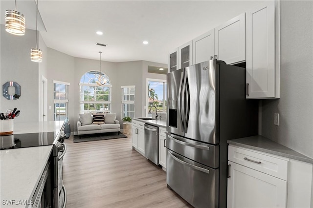 kitchen with sink, light hardwood / wood-style flooring, appliances with stainless steel finishes, white cabinets, and decorative light fixtures