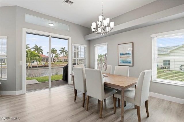 dining room with light hardwood / wood-style flooring, plenty of natural light, and a chandelier