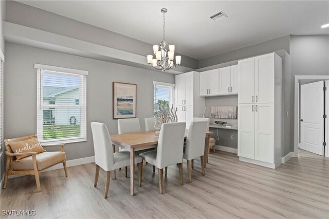 dining area with an inviting chandelier and light hardwood / wood-style flooring