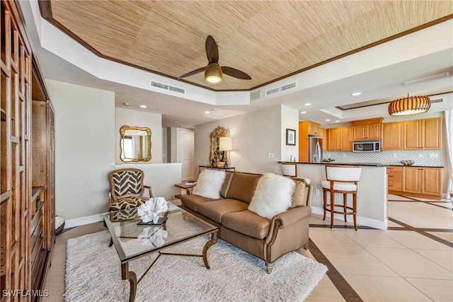 tiled living room featuring ceiling fan, wood ceiling, a tray ceiling, and crown molding