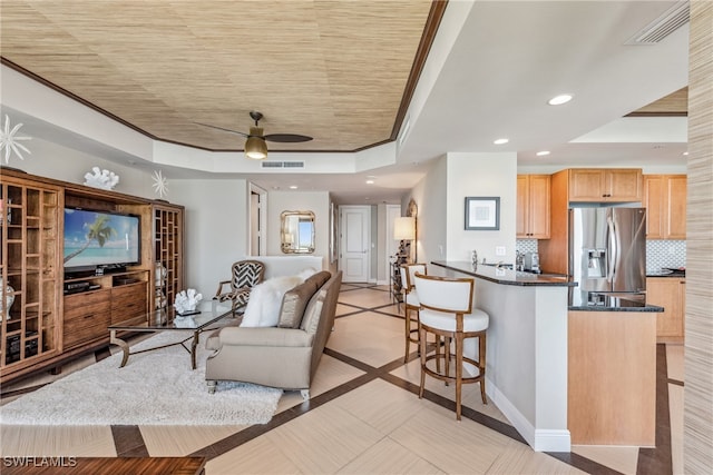 living room with a tray ceiling, ceiling fan, and crown molding