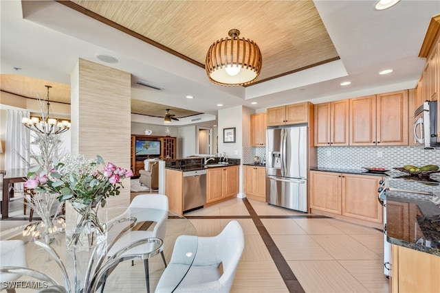 kitchen featuring kitchen peninsula, appliances with stainless steel finishes, tasteful backsplash, a tray ceiling, and hanging light fixtures