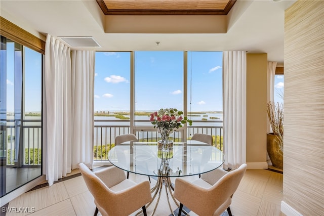 dining space with a water view, a wealth of natural light, and a tray ceiling