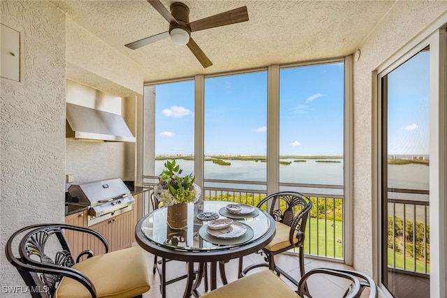 sunroom / solarium featuring ceiling fan and a water view