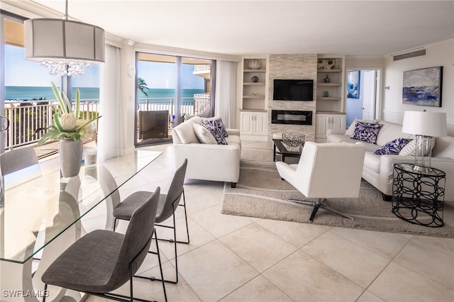 tiled living room with a stone fireplace, a water view, built in features, and crown molding