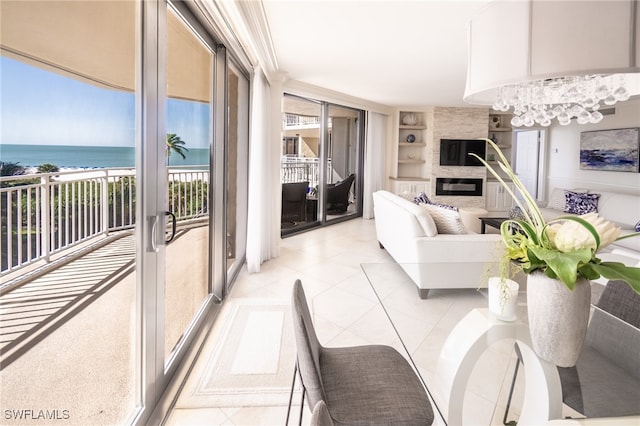 living room featuring light tile patterned floors, a water view, built in features, a fireplace, and a chandelier