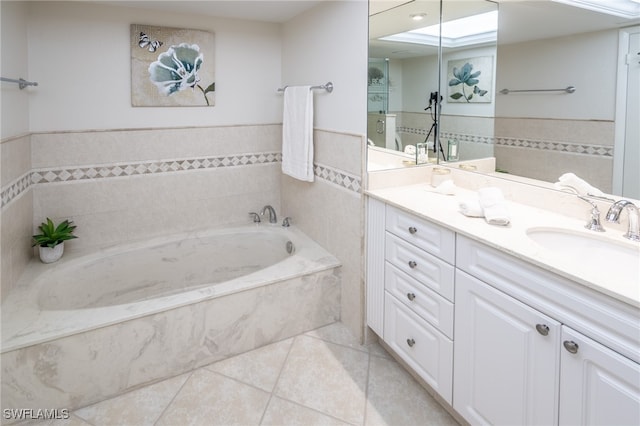 bathroom with tile patterned flooring, vanity, tile walls, and tiled bath