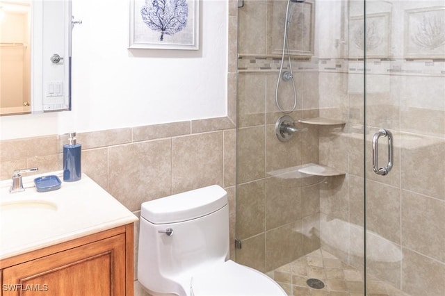 bathroom with vanity, toilet, an enclosed shower, and tile walls