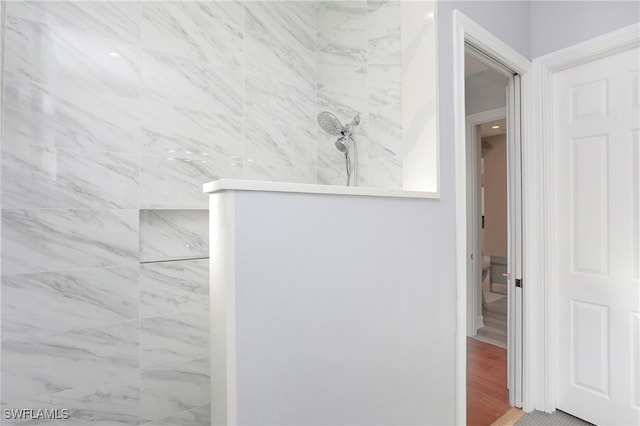 bathroom with tiled shower and wood-type flooring