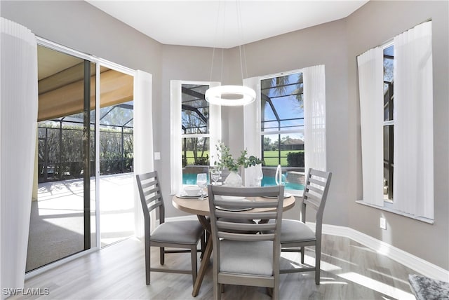 dining area featuring wood-type flooring, an inviting chandelier, and a wealth of natural light