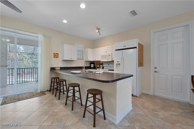 kitchen with white appliances, white cabinets, a kitchen breakfast bar, sink, and kitchen peninsula