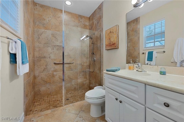 bathroom featuring tile patterned floors, vanity, toilet, and a tile shower