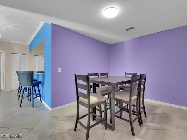 dining area with light tile patterned floors and ornamental molding