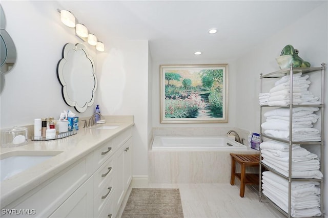 bathroom with tiled tub and vanity