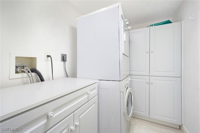 laundry area featuring cabinets and stacked washer and dryer