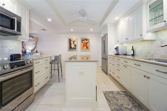 kitchen with white cabinetry, backsplash, a breakfast bar, a kitchen island, and appliances with stainless steel finishes