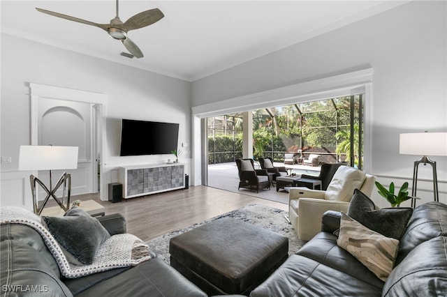 living room featuring wood-type flooring, ceiling fan, and ornamental molding