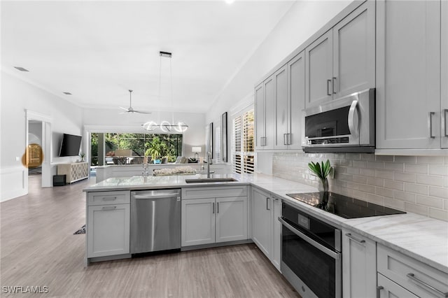 kitchen featuring pendant lighting, appliances with stainless steel finishes, gray cabinets, and sink