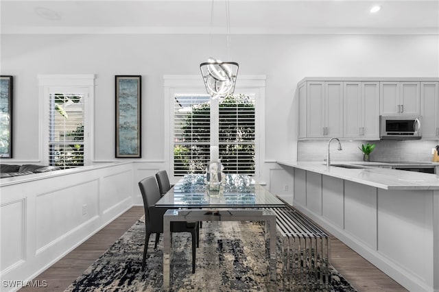 dining area with sink, dark hardwood / wood-style floors, and a chandelier