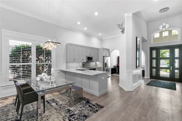 kitchen with decorative light fixtures, kitchen peninsula, stainless steel appliances, and an inviting chandelier