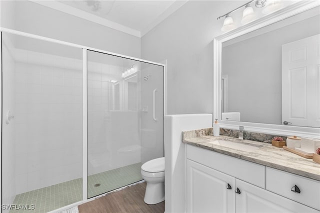 bathroom featuring crown molding, hardwood / wood-style floors, toilet, a shower with shower door, and vanity