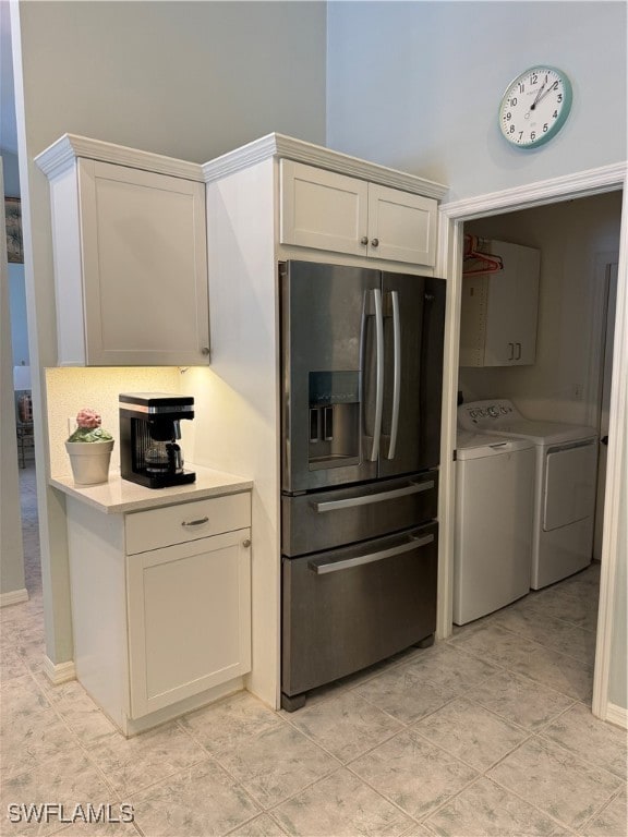 kitchen featuring washer and clothes dryer, light tile patterned flooring, white cabinetry, and stainless steel refrigerator with ice dispenser