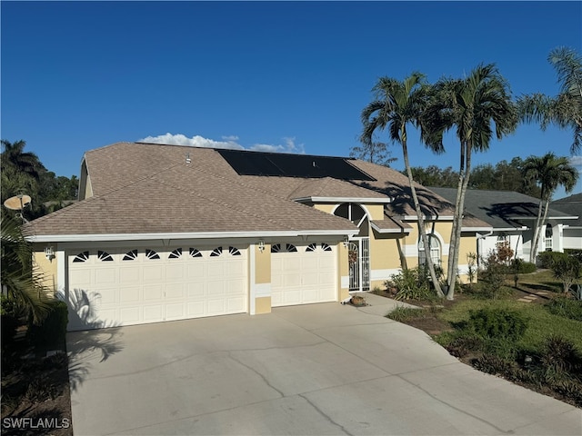 ranch-style home with a garage and solar panels