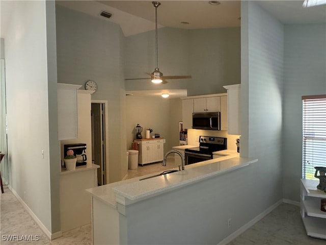 kitchen with kitchen peninsula, stainless steel appliances, sink, decorative light fixtures, and white cabinetry