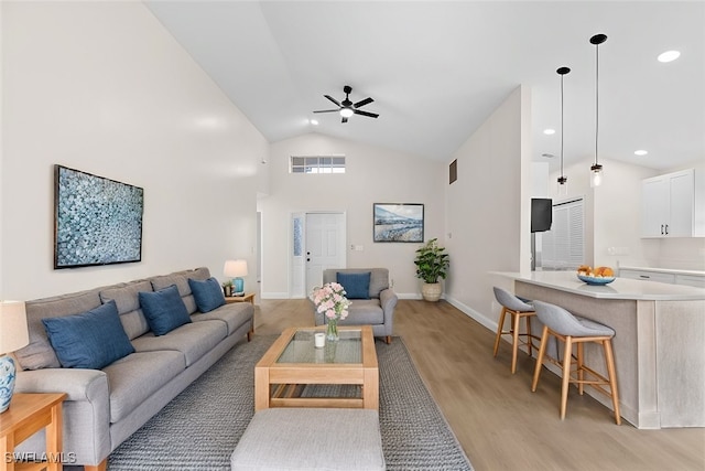 living room with ceiling fan, light wood-type flooring, and high vaulted ceiling