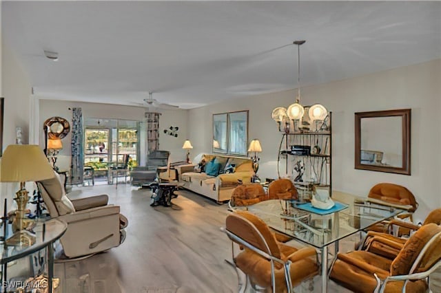 dining room with light hardwood / wood-style flooring and ceiling fan with notable chandelier