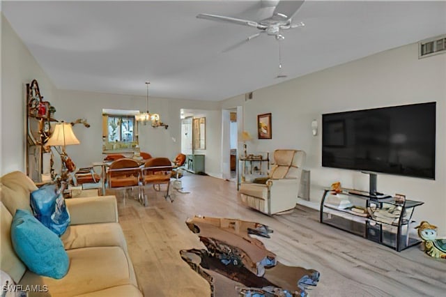 living room with ceiling fan with notable chandelier and light hardwood / wood-style flooring