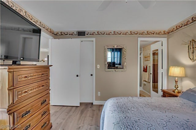 bedroom featuring ceiling fan, light wood-type flooring, ensuite bathroom, and a closet