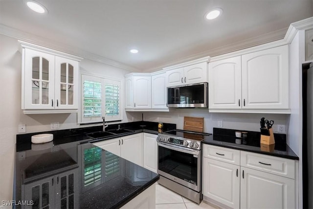 kitchen featuring appliances with stainless steel finishes, white cabinets, a sink, and glass insert cabinets