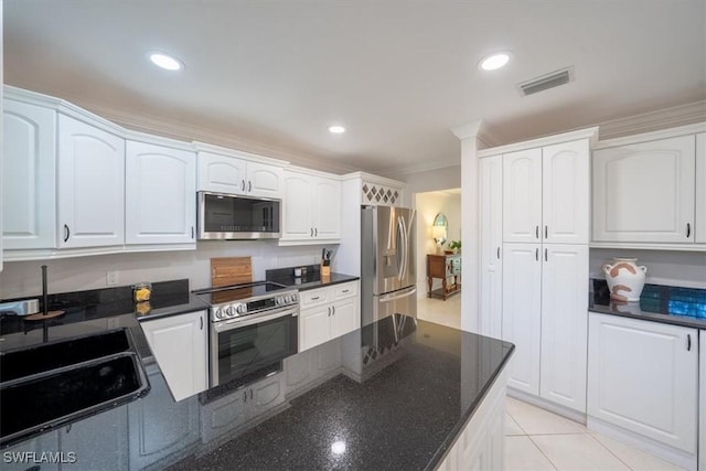 kitchen with a sink, visible vents, white cabinets, appliances with stainless steel finishes, and dark stone counters