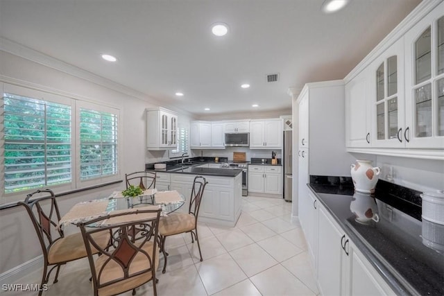 kitchen featuring dark countertops, ornamental molding, stainless steel appliances, and white cabinets