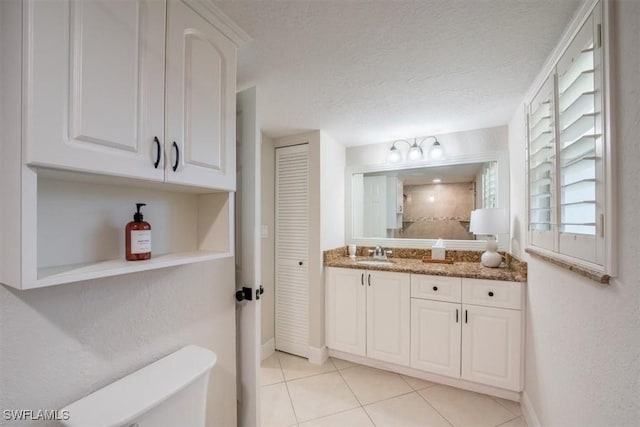 bathroom featuring a textured ceiling, vanity, baseboards, a closet, and tile patterned floors