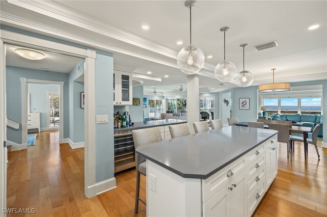 411 Bella Vista Way E, Sanibel, FL 33957 - kitchen with a kitchen bar, dark countertops, white cabinets, light wood-type flooring, and ornamental molding
