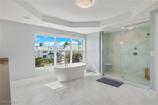 bathroom featuring a raised ceiling and independent shower and bath