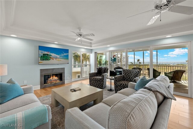 411 Bella Vista Way E, Sanibel, FL 33957 - living area with ceiling fan, a tray ceiling, a glass covered fireplace, healthy amount of natural light, and crown molding
