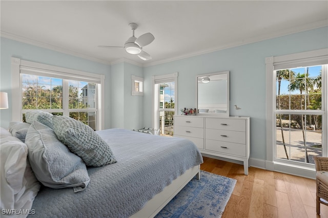 bedroom featuring ceiling fan, crown molding, light hardwood / wood-style flooring, and multiple windows