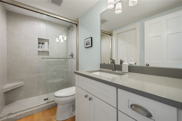 bathroom featuring hardwood / wood-style floors, vanity, a shower with door, and toilet