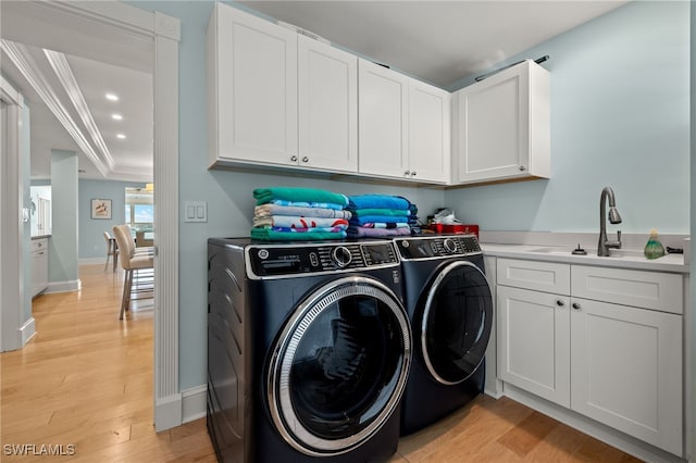 laundry room with washing machine and clothes dryer, sink, cabinets, light hardwood / wood-style flooring, and crown molding