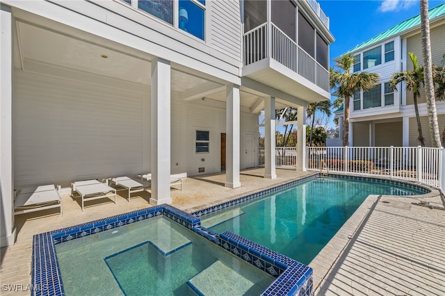 view of swimming pool with a sunroom, an in ground hot tub, and a patio