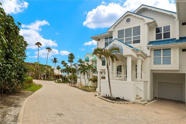 411 Bella Vista Way E, Sanibel, FL 33957 - view of front of house with decorative driveway, an attached garage, a standing seam roof, a porch, and metal roof
