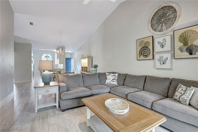 living room featuring baseboards, high vaulted ceiling, light wood finished floors, and a notable chandelier