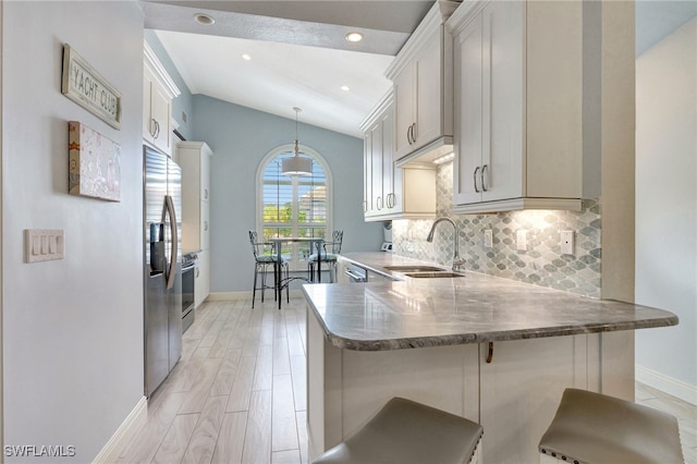 kitchen featuring sink, a kitchen breakfast bar, kitchen peninsula, pendant lighting, and lofted ceiling